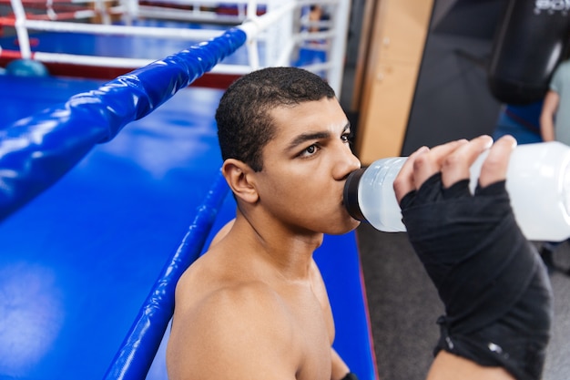 Male boxer drinking water in gym