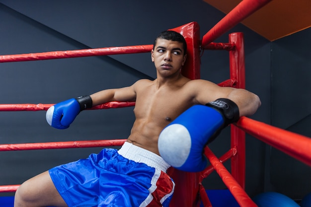 Photo male boxer sitting in the corner of the boxing ring