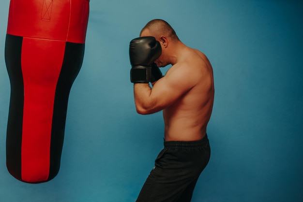 Male boxer training with punching bag in dark sports hallMale boxer as exercise for the big fight Boxer hits punching bag