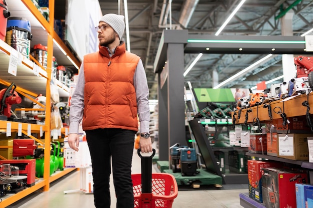 A male builder in a hardware store buys a tool for wall plastering