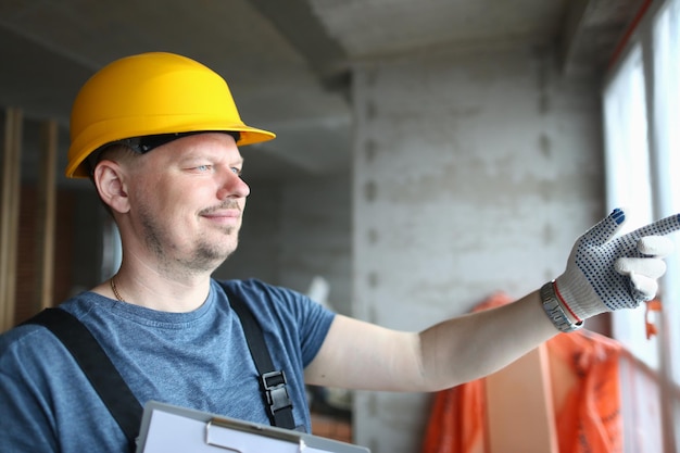 Male builder in helmet looks out window at construction site