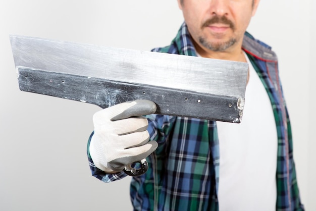 A male builder holds a spatula in his hand on a white background closeup