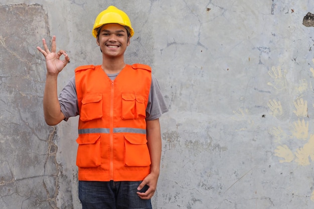 Male builder or manual worker in yellow helmet shows ok sign Mechanical worker making gesture okay