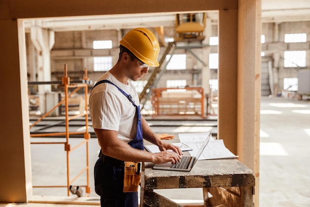 Male builder using modern laptop at work