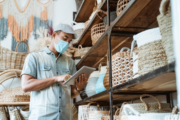 L'imprenditore maschio indossa maschere per il viso nel suo negozio di arte e artigianato