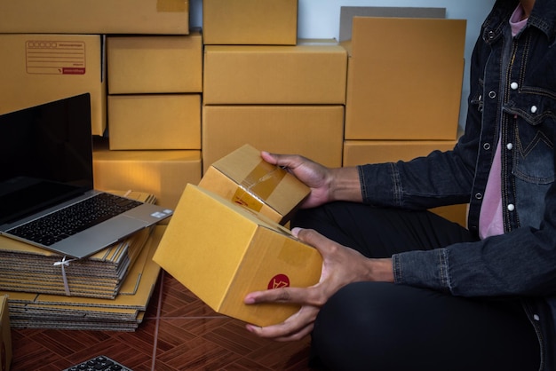 Male business owner working packing the order for shipping to\
customer working with laptop