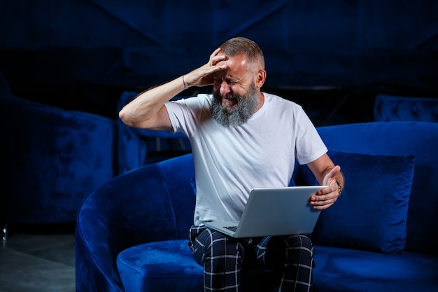 Male businessman sits with a cup of coffee and makes a new project with grimaces on his face.