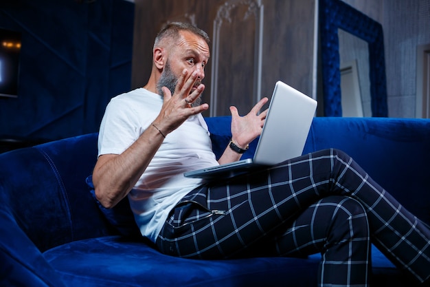 Male businessman sits with a cup of coffee and makes a new project with grimaces on his face.