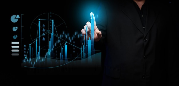 A male businessman stands in a black suit in front of a holographic ddiagram with graphs and growing indicators. Business growth, sales increase. High performance