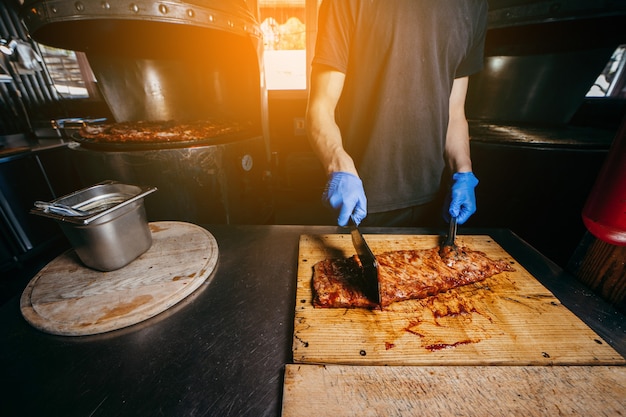 Male butcher or chef is preparing prime rib steaks from a large beef rib roast