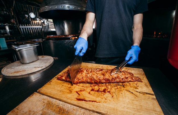 Male butcher or chef is preparing prime rib steaks from a large beef rib roast