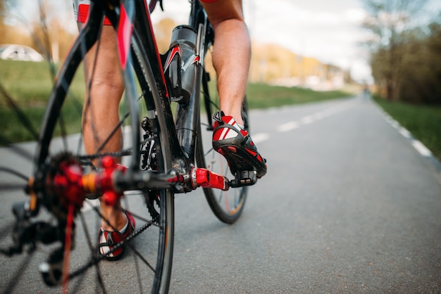 Male bycyclist rides on bike path, view from the rear wheel.