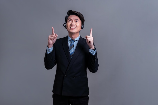 Male call center operator wearing headset making finger pointing Jubilant