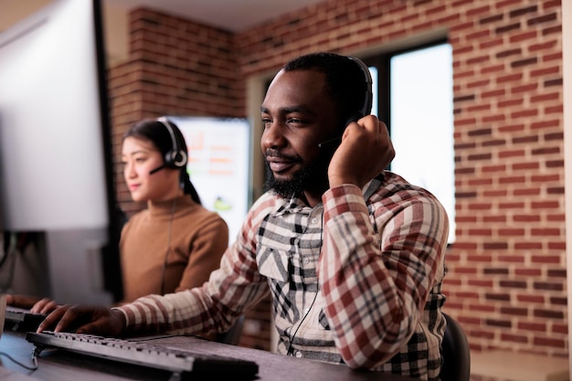 Male call center receptionist talking to clients on helpline, giving telemarketing assistance to people at customer care service. Helpdesk support consultant working at network reception.