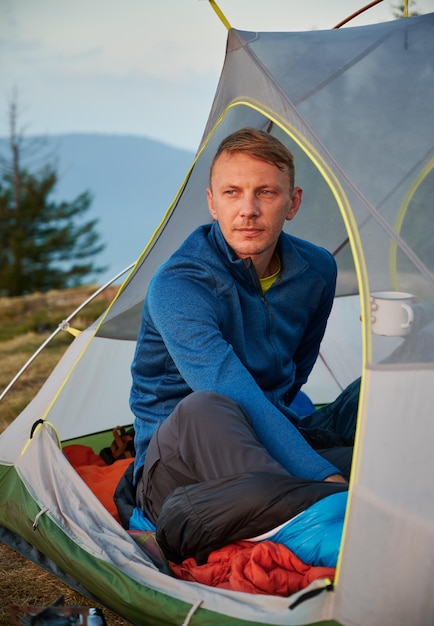 Male camper relaxing in tent in the mountains