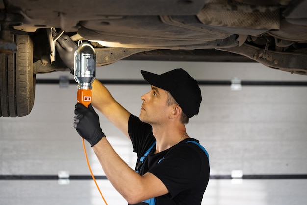 Male car mechanic checking car auto mechanic working underneath car lifting machine at the garage