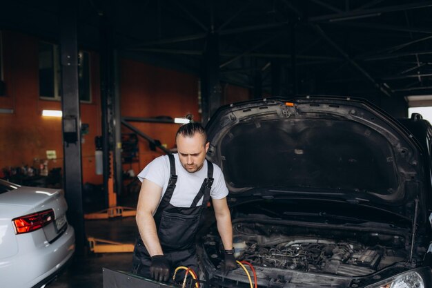 Male car mechanic filling up car air conditioner and check the compressor oil system caused by the car air conditioner is not cold