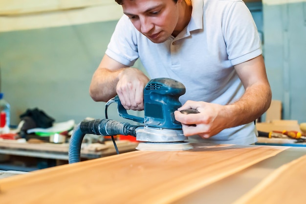 Photo male carpenter sanding wood in carpentry workshop