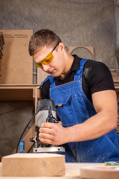 Male carpenter using electric sander to polish wooden plank in joinery workshop