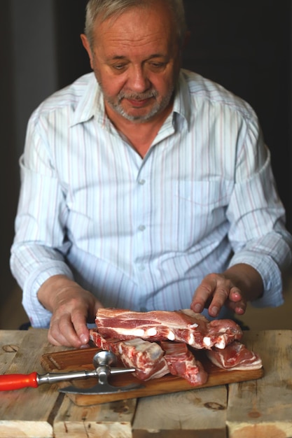 A male chef cuts raw pork ribs