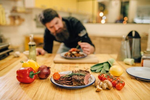 Photo male chef decorates with herbs a meat dish for gourmets