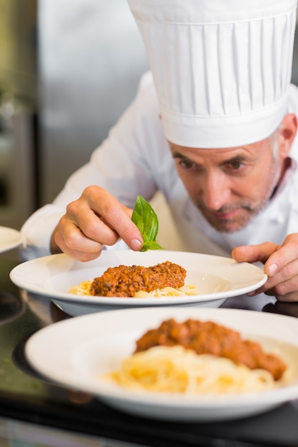 Foto cuoco unico maschio che guarnisce alimento in cucina