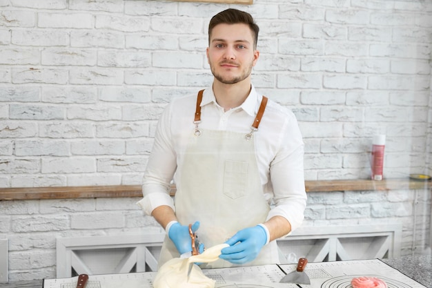 Шеф-повар в перчатках отрезает ножницами кусок горячих карамельных леденцов на палочке