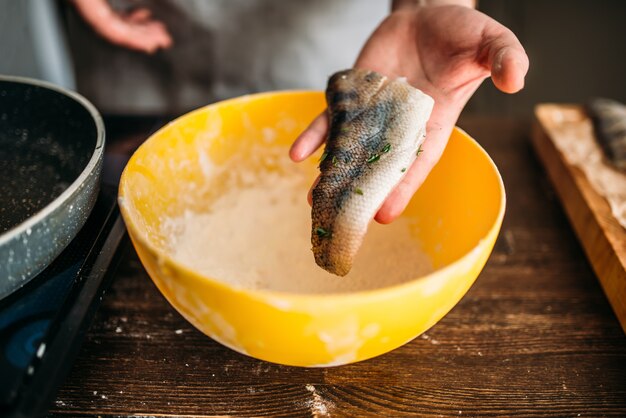 男性シェフの手がフライパンで魚料理