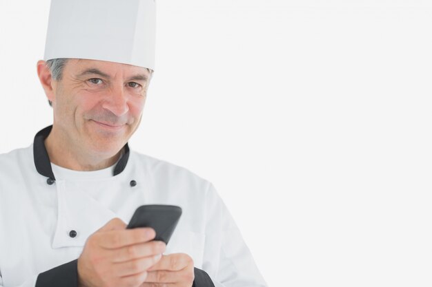 Мужской шеф-повар, держащий сотовый телефон