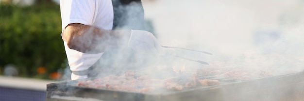 Male chef preparing barbecue on grill in restaurant closeup