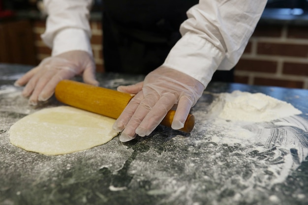 Male chef uses ingredients for preparing flour products on the kitchen table