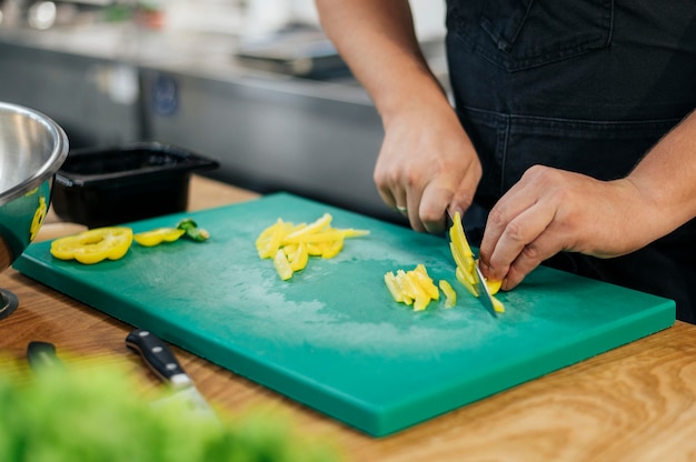 キッチンで野菜をスライスするエプロンを持つ男性シェフ