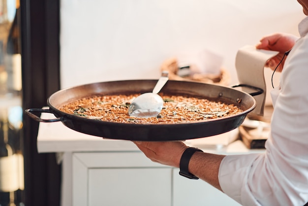 Foto chef maschio con un piatto di paella nelle sue mani