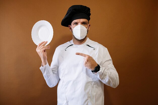 Photo male chef with mask and an empty plate