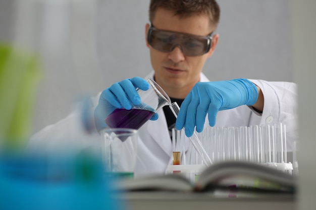 Photo a male chemist holds test tube of glass in his hand overflows a liquid solution