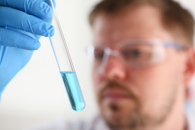 A male chemist holds test tube of glass in his hand overflows