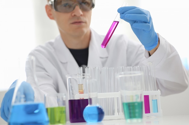 A male chemist holds test tube of glass