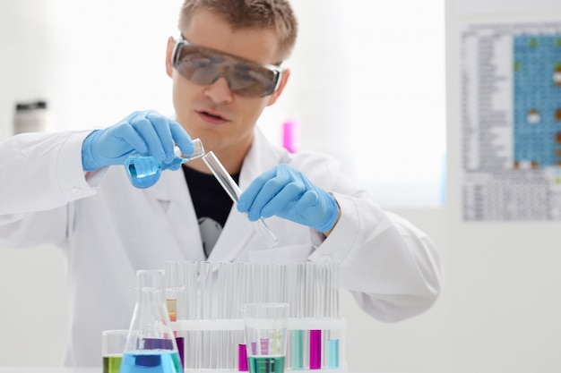 A male chemist holds test tube of glass in