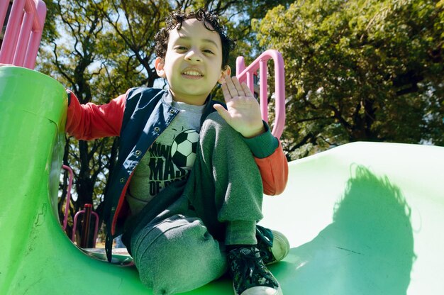 Male child sitting on public park playground happy looking at camera