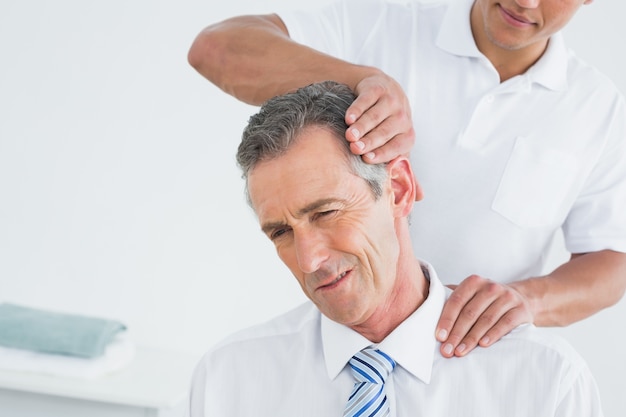 Male chiropractor doing neck adjustment