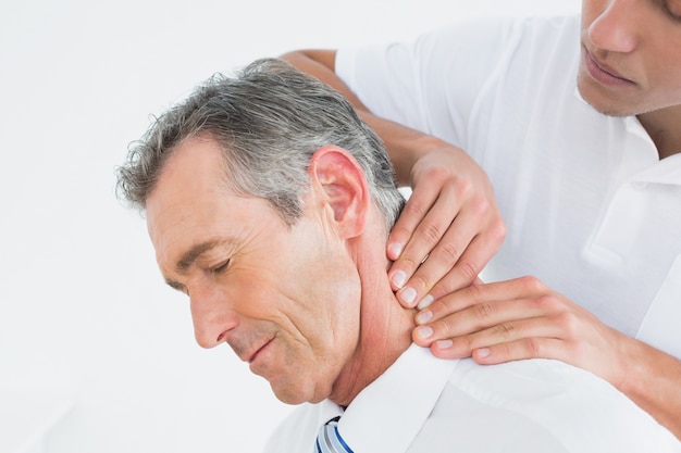 Male chiropractor massaging patients neck