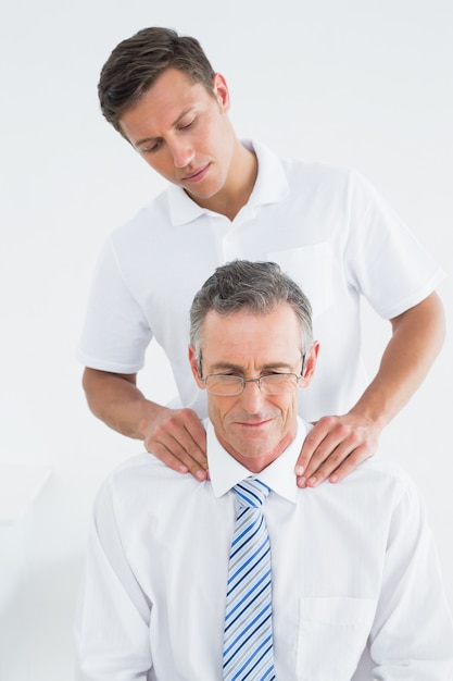 Male chiropractor massaging patients neck