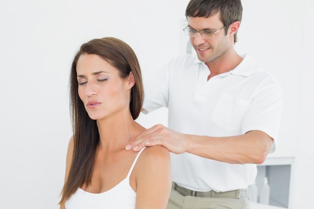 Male chiropractor massaging a young womans shoulder