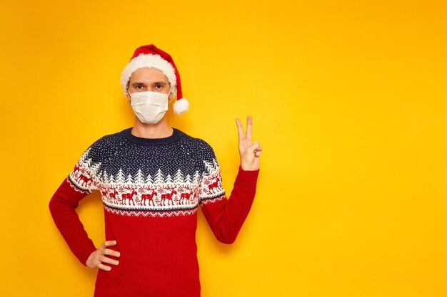 Photo male in christmas sweater with reindeer shows sign v victory peace isolated yellow background