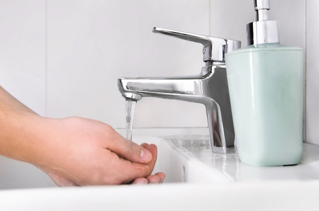 男性の手の洗浄。ウイルスから保護するために石鹸で手を洗う