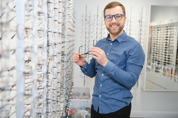 Male client chooing new eyeglasses frame for his new eyeglasses in optical store