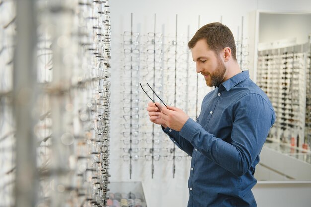 Male client chooing new eyeglasses frame for his new eyeglasses in optical store