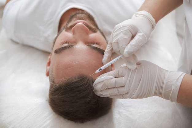 Male client getting hairloss injections treatment in beauty clinic