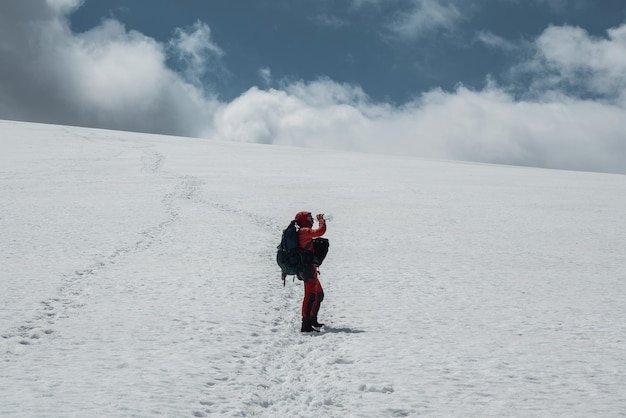 男性登山家は、雪に覆われた山腹で登山中に水を飲みます。