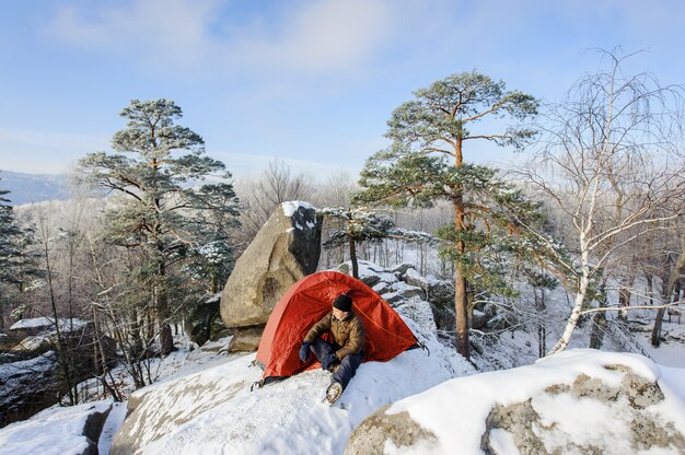 男性の登山家は岩の上に彼のテント近く